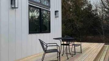 Een modern terras buiten met metalen meubilair en twee wandlampen.