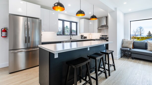 A modern kitchen with a large island, stainless steel appliances, and pendant lighting. - Cozy Modern Cottage - Walking distance to 5 beach access points (Tiny)