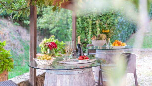 Ein Glastisch mit einer Champagnerflasche, Gläsern, einer Obstschale und einem Blumenstrauß.