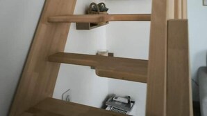 Une étagère en bois, de type échelle, avec plusieurs niveaux, dont certains contiennent de petits objets.