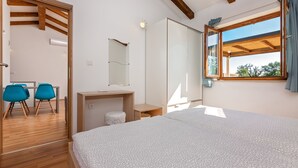 Ein Schlafzimmer mit einem großen Bett, einem Schreibtisch, einem Stuhl, einem Spiegel und einem Fenster mit Vorhängen.