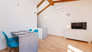 Eine moderne Küche mit Essbereich, Holzbalken und einem Fernseher auf einem weißen Schrank.