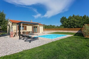 Una casa con piscina, terraza techada y césped.