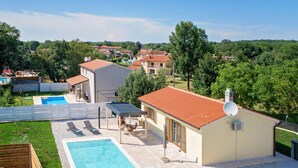 Ein Wohnhaus mit Swimmingpool, Sitzgelegenheiten im Freien und Blick auf umliegende Häuser.