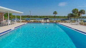 A rectangular swimming pool with two buoys, surrounded by lounge chairs and a covered seating area. - The Red Sisters Retreat.  (Edgewater)