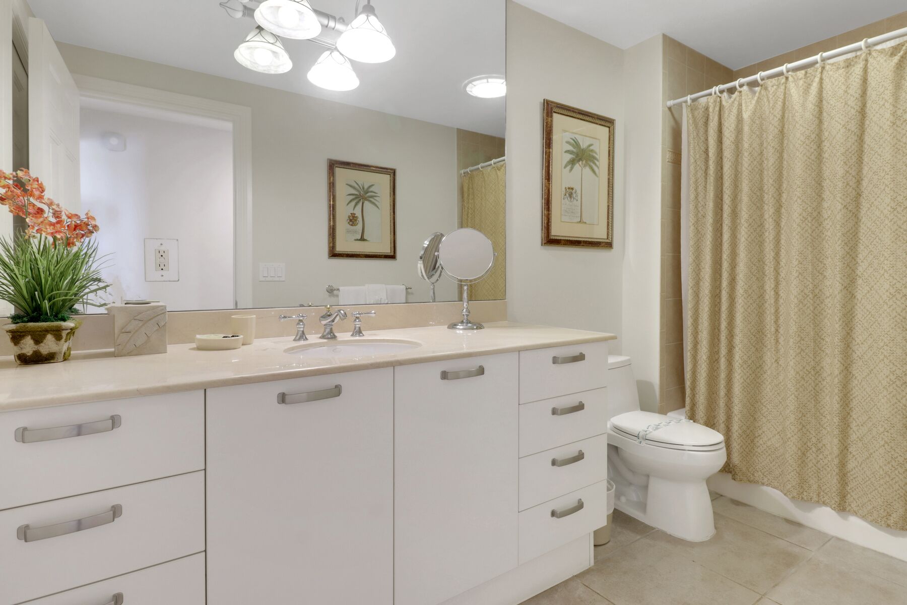 A bathroom with a white vanity, a sink, a mirror, a toilet, and a shower curtain.