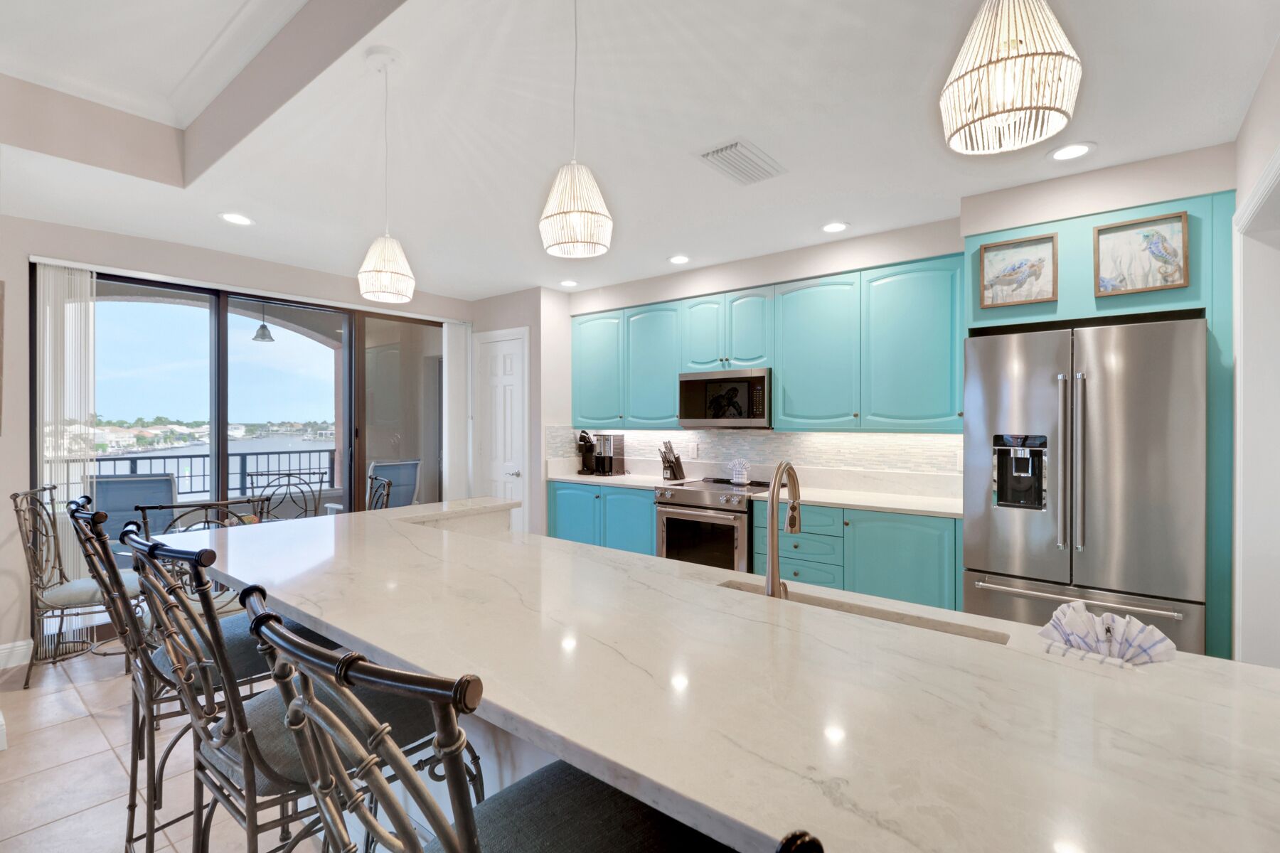 Une cuisine moderne avec des armoires de couleur turquoise, des appareils électroménagers en acier inoxydable et un grand îlot central.