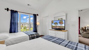 A hotel room with two beds, a TV, a dresser, and a view of buildings outside. - Myrtlewood Top floor Condo 2BR • 4 Beds • 2 full Baths • with Elevator (Myrtle Beach)