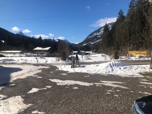 Schneebedeckte Landschaft mit einer Straße, Gebäuden und Bergen im Hintergrund.