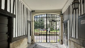 Un couloir avec une grille en fer noir donnant accès à un espace extérieur.