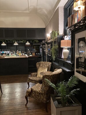 A bar area with a counter, bar stools, and a bookshelf with books and decorative items.
