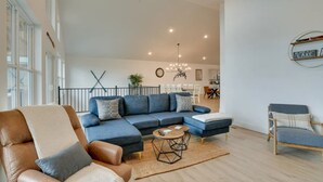 A modern living room with a sectional sofa, a coffee table, and a leather armchair. There is a dining area in the background with a chandelier. - Branson Vacation Rental w/ Table Rock Lake Views!  (Branson)