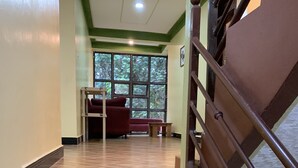 A staircase with a metal railing leading to a room with a red sofa and a small table. - Mpanga Nature Center  (Mpigi)