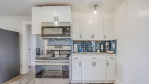 A modern kitchen with white cabinets, a stainless steel stove, and a microwave. - Weymouth Apartment: Close to Beaches & Boston! (Weymouth)