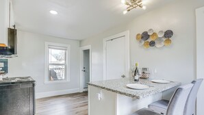 A kitchen with a granite countertop, a built-in oven, and a dining area with a bench and chairs. - Weymouth Apartment: Close to Beaches & Boston! (Weymouth)