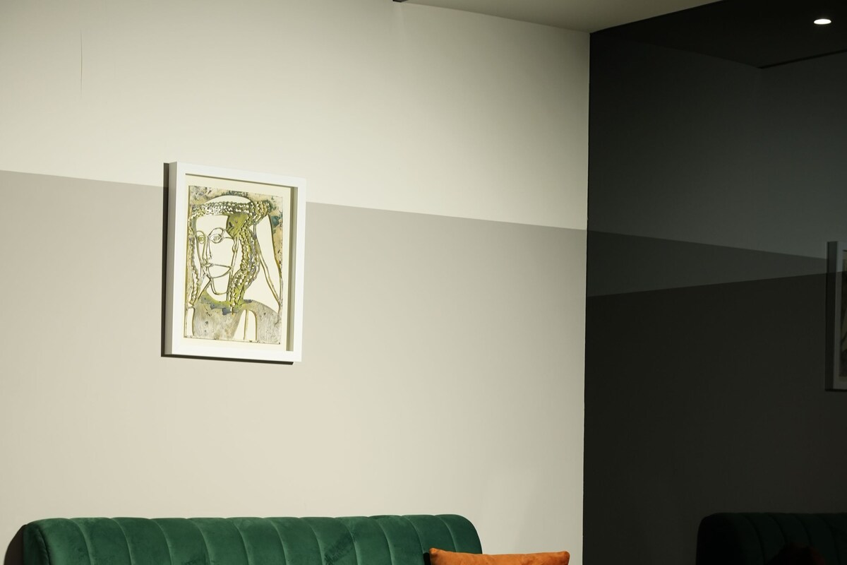 A modern hotel room with a green sofa, a small coffee table, and a framed artwork on the wall.
