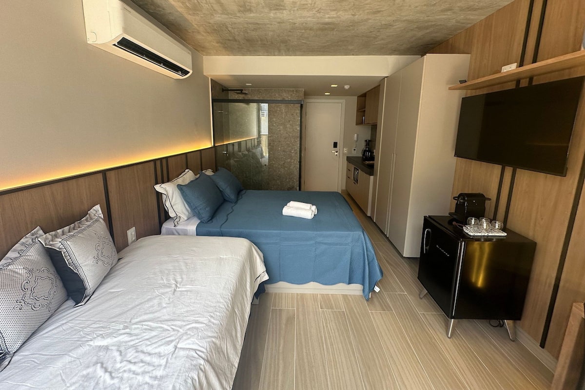 Een hotelkamer met twee bedden, een televisie, een koffiezetapparaat en een minibar.