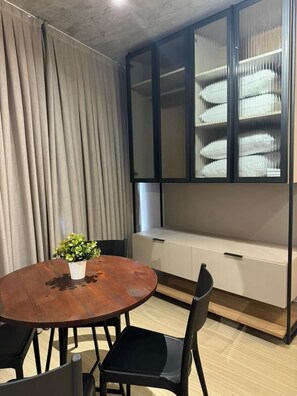 Une pièce avec une table ronde en bois, des chaises noires, une plante en pot, un banc intégré avec espace de rangement et une vitrine.