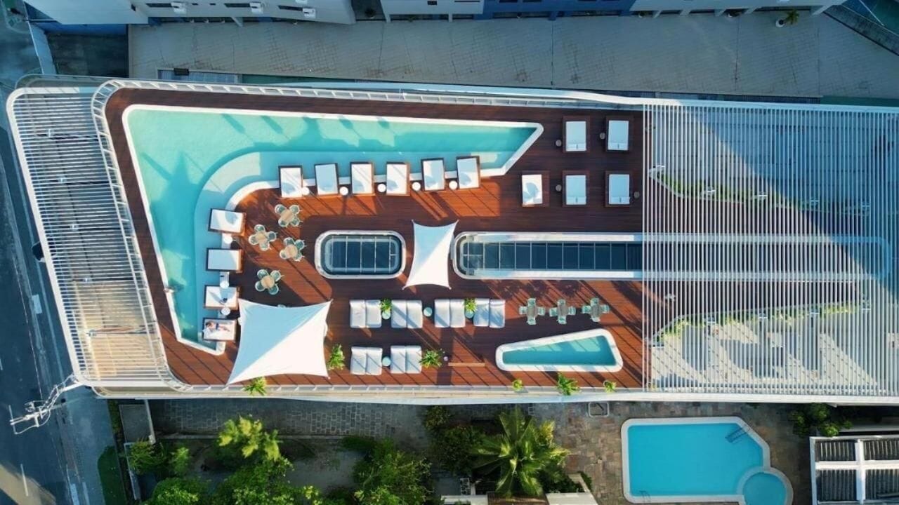 Vista aérea de la cubierta de un crucero con piscina, tumbonas y un área de estar cubierta.