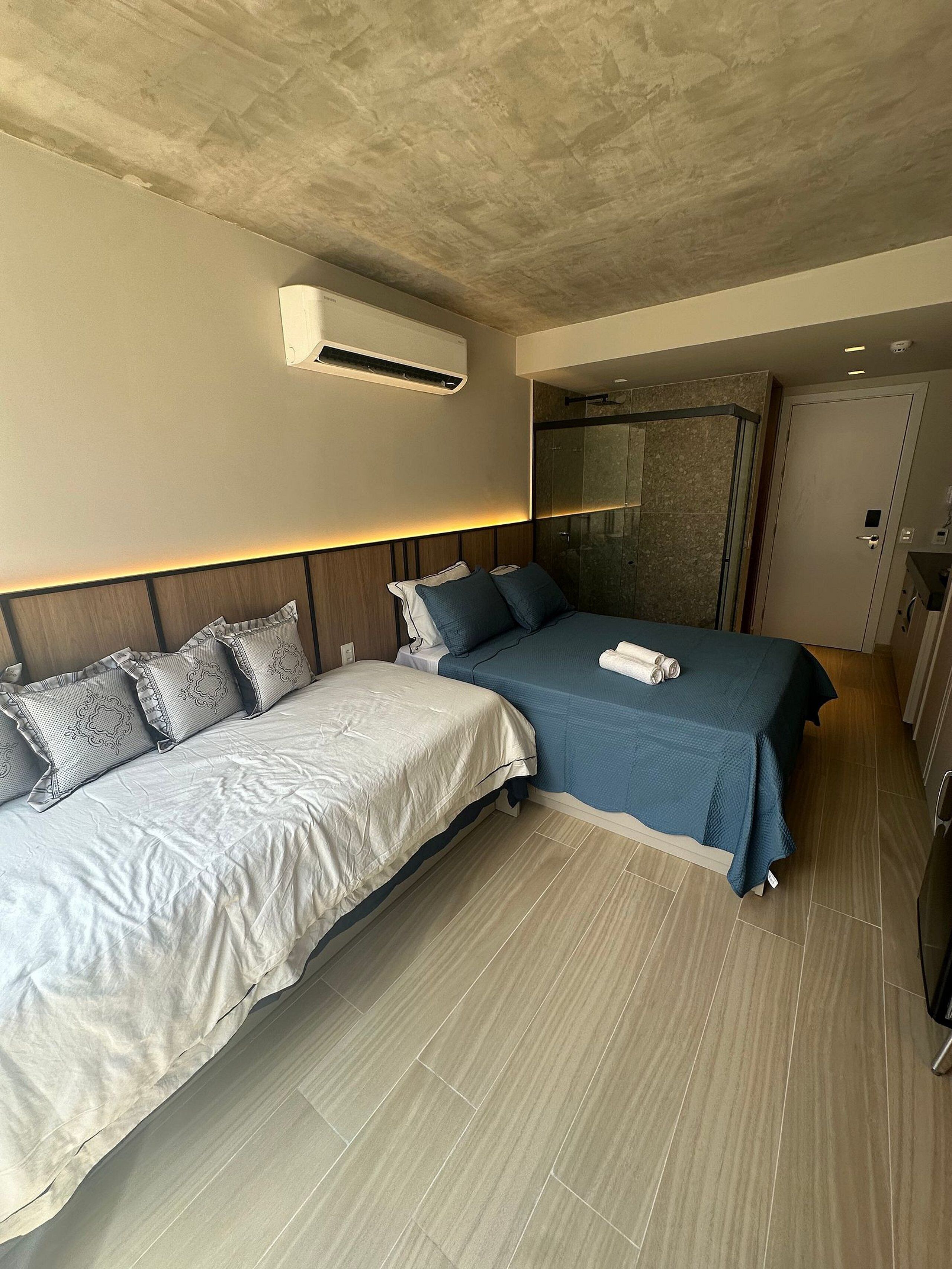 Habitación de hotel con dos camas, zona de ducha y una puerta.