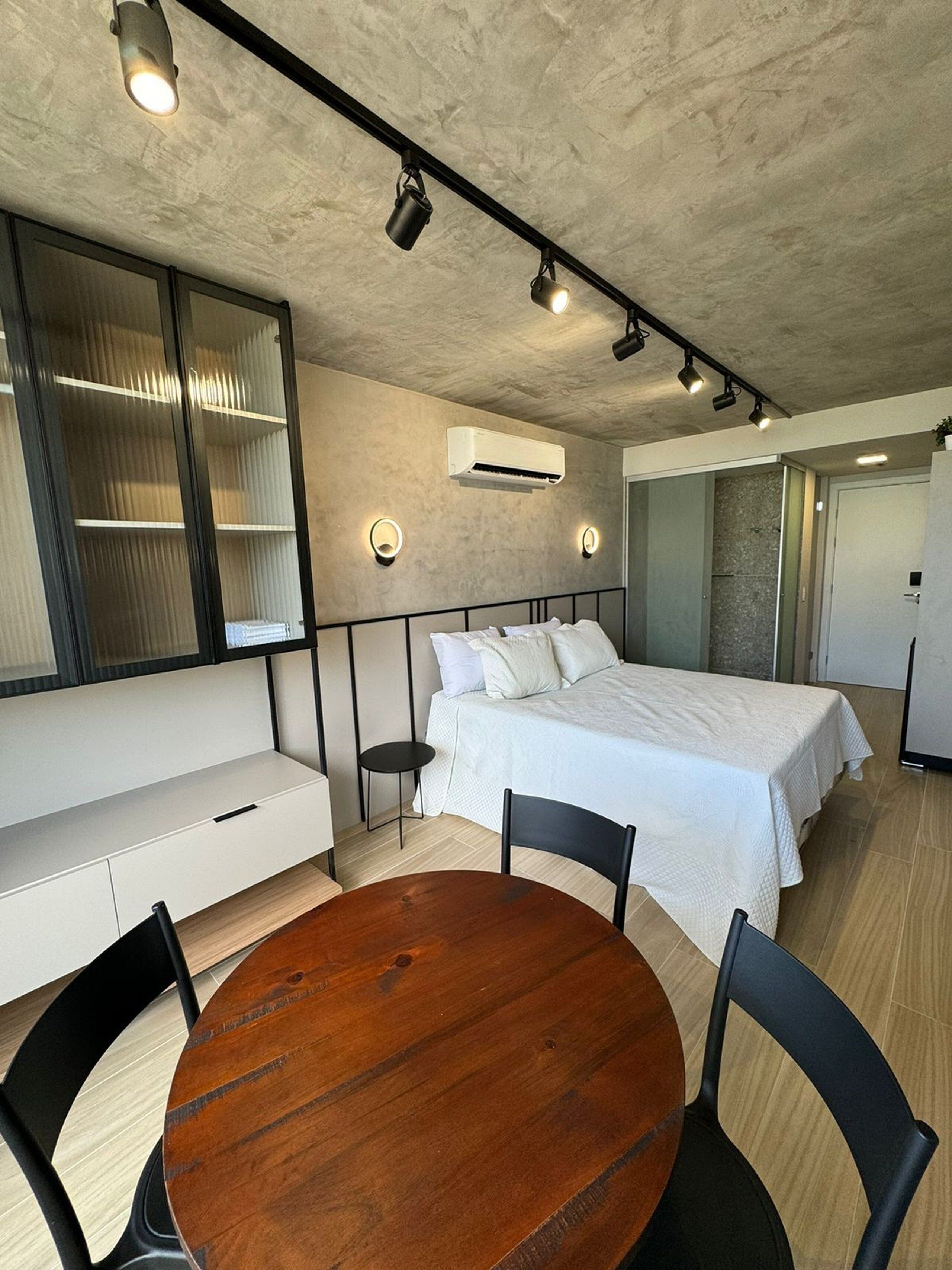 Une chambre moderne avec un lit, des tables de chevet, une table ronde en bois et des chaises.