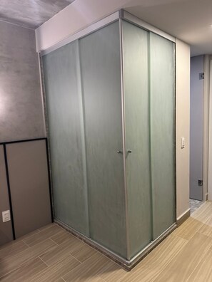 Une pièce dotée d’une grande porte coulissante, d’un plancher de couleur claire et offrant une vue partielle sur une porte menant à une autre pièce.