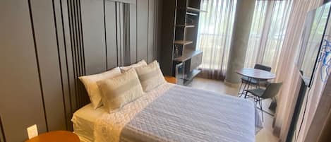 A modern bedroom with a large bed, a small table, and a chair.