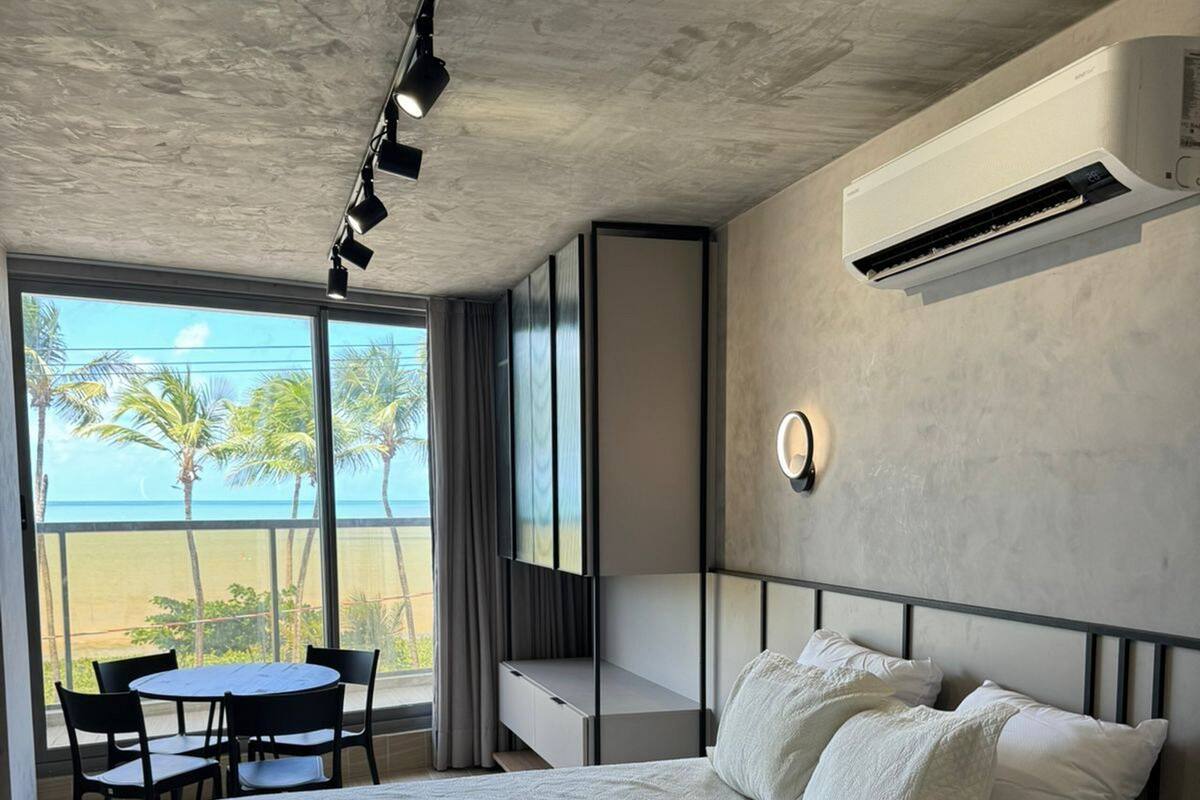 Een slaapkamer met een groot bed, een bureau, een stoel en uitzicht op de oceaan.