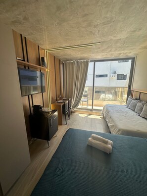 Une chambre d’hôtel avec un lit, un bureau, une télévision et une vue sur la ville.