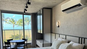 Een slaapkamer met een groot bed, een bureau, een stoel en uitzicht op de oceaan.