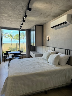 Een slaapkamer met een groot bed, een bureau, een stoel en uitzicht op de oceaan.