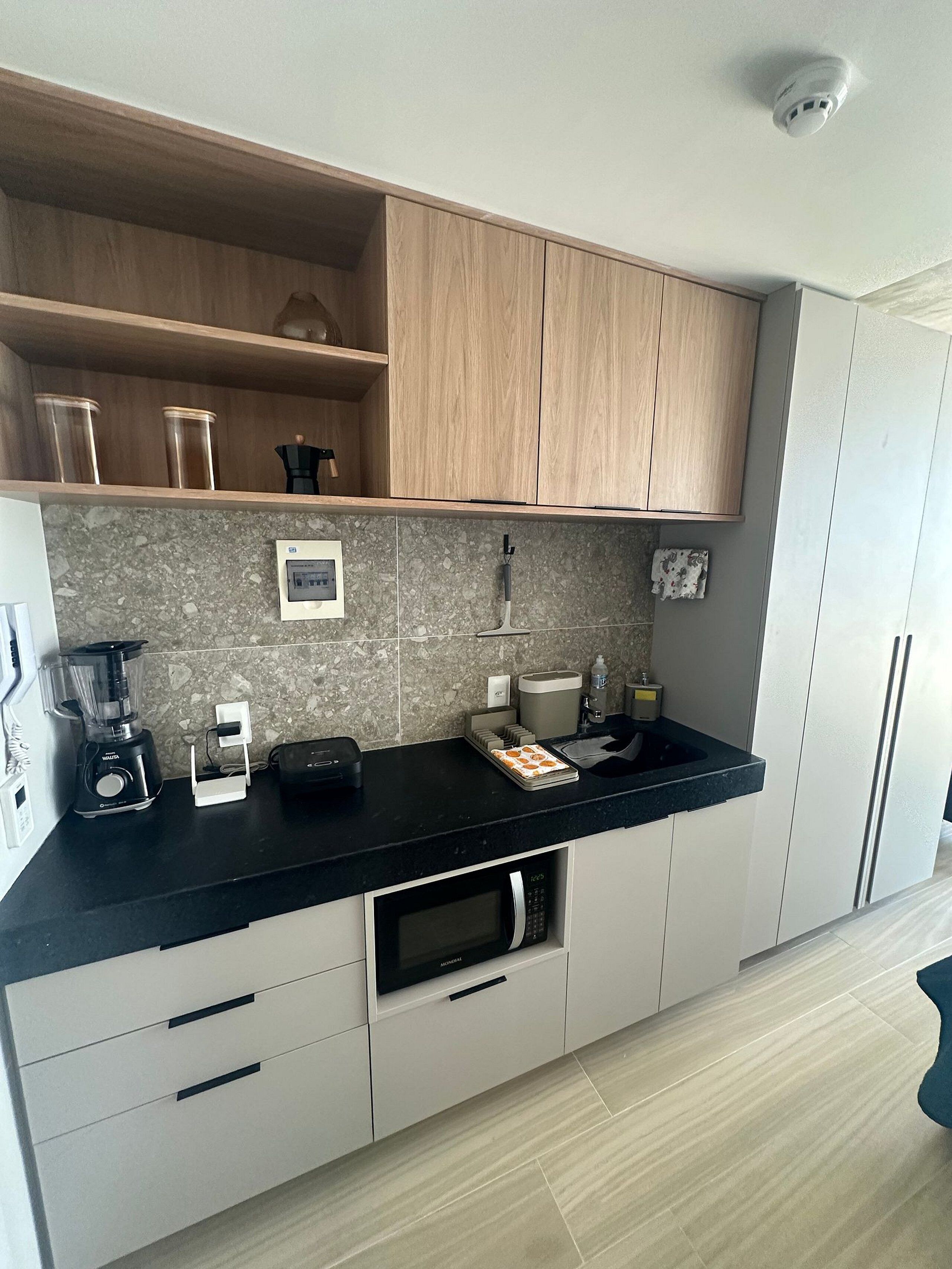 Eine moderne Küche mit schwarzem Arbeitsplatz, Holzschränken, einer eingebauten Mikrowelle und einer Kaffeemaschine.