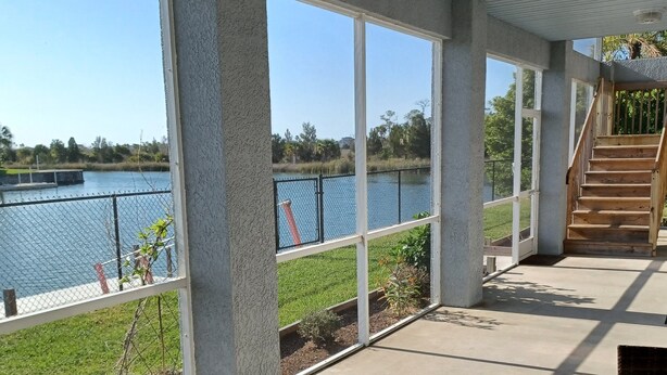 A covered patio with a view of a lake, concrete flooring, and wicker furniture. - Newly remodeled gulf canal home w/floating dock and kayaks (Hernando Beach)