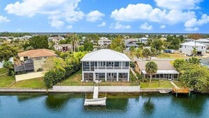 A waterfront property with a large house featuring a covered patio and a dock. - Newly remodeled gulf canal home w/floating dock and kayaks (Hernando Beach)