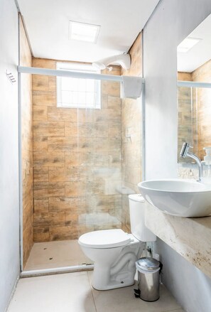 Ein modernes Badezimmer mit Steinwand, Duschkabine, Toilette und Waschbecken mit Spiegel.