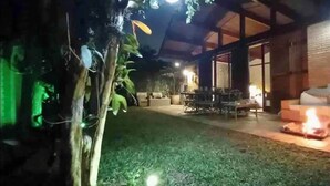 An outdoor patio area with a fire, a dining table, and a sofa.