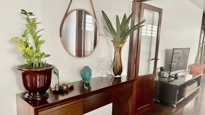 A wooden console table with a mirror, a potted plant, a Buddha statue, and a decorative vase.