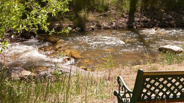 A bench by a flowing stream with rocks and greenery. - Premium full-hookup drive-through RV 1 space with direct access to  Paiute Trail (Marysvale)