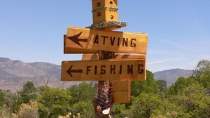 A wooden sign with directions for ATVING and FISHING, set against a mountainous backdrop. - Premium full-hookup drive-through RV 1 space with direct access to  Paiute Trail (Marysvale)
