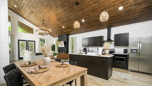 Une cuisine moderne avec une table à manger en bois, des chaises noires et un îlot central.