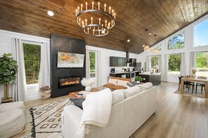 Amplia sala de estar con chimenea, un sofá grande y un comedor con mesa y sillas.