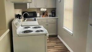 A compact kitchen with a stove, microwave, and cabinets.