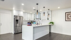A modern kitchen with white cabinetry, a stainless steel refrigerator, and a central island with a sink. - Pool and Beautiful Tempe - Scottsdale Home! (Tempe)
