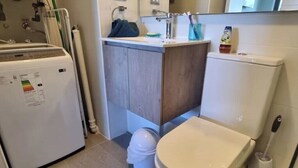 Une petite salle de bain comprenant des toilettes, un lavabo et un lave-linge.