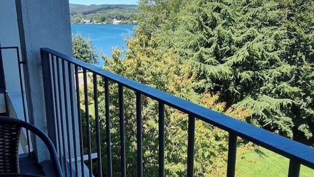 Un balcon donnant sur un lac et une forêt dense.