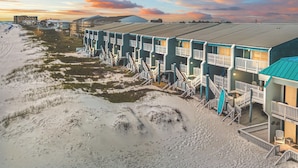 A beachfront hotel with multiple-story buildings, each with balconies and a beach access walkway.