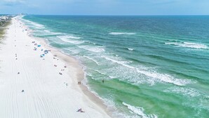 A beach with a long stretch of sand, waves, and a clear sky.