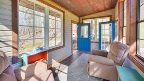 A cozy room with large windows, a blue door, and wicker furniture. - Nautical Retreat at Kudzu Cove Cabins Resort (Guntersville)