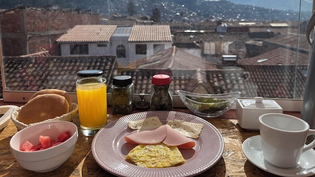 Una mesa de desayuno con un plato de comida, un vaso de jugo de naranja y aderezos.