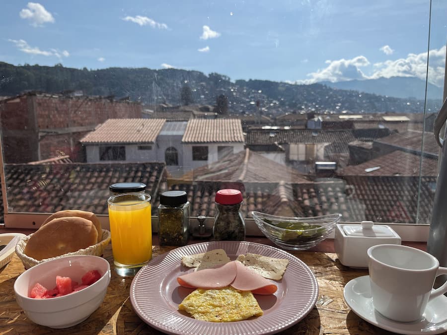 Una mesa de desayuno con un plato de comida, un vaso de jugo de naranja y aderezos.